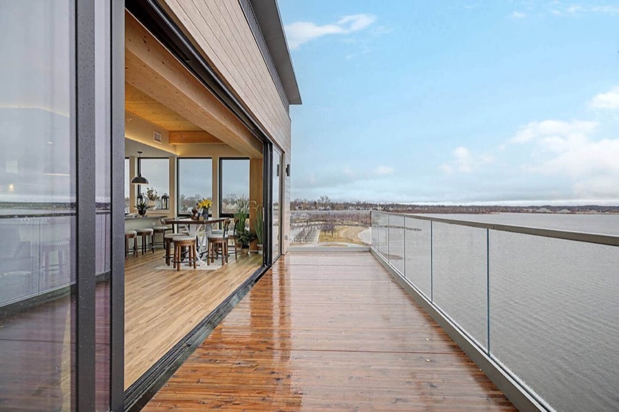 The private glass-railed balcony running along the top floor, with Muskegon Lake stretching to the horizon